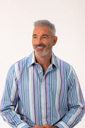 A smiling middle-aged man with gray hair wearing a long-sleeve button-up shirt with vertical stripes in blue, purple, and white, set against a plain white studio background.