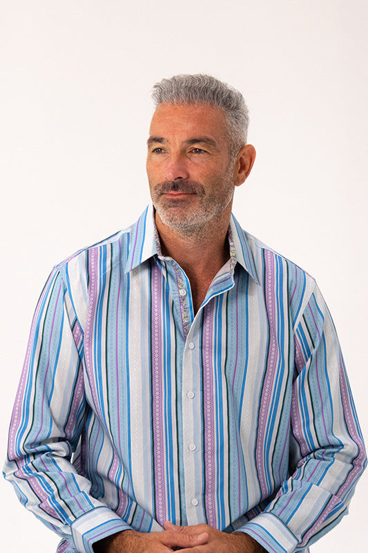 A man with gray hair and a beard wearing a long-sleeve button-up shirt with vertical stripes in blue, pink, and white, photographed against a plain white background.