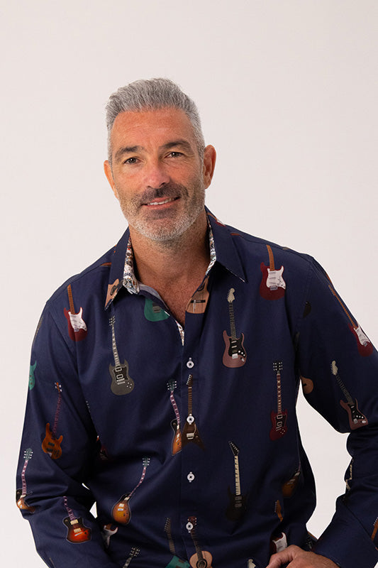 Man wearing a navy blue shirt with guitar pattern on a white background