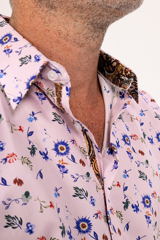 Close-up of a man wearing a light pink button-down shirt with a colorful floral print and a patterned inner collar.