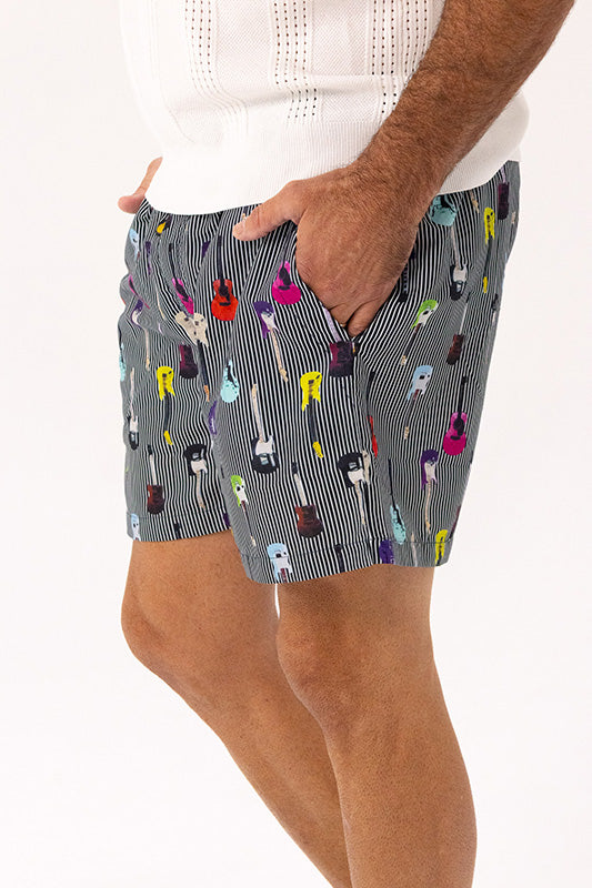a man has his hand in the side pocket of a pair of grey pin stripe swim shorts with colourful guitar pattern.