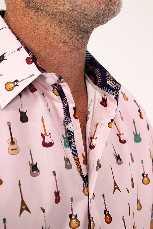 Close-up of a man wearing a light pink button-up shirt with an all-over guitar print and a patterned inner collar.