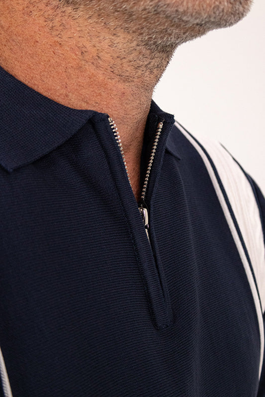 Close-up of a man wearing a navy blue polo shirt with a half-zip collar and white shoulder stripes.